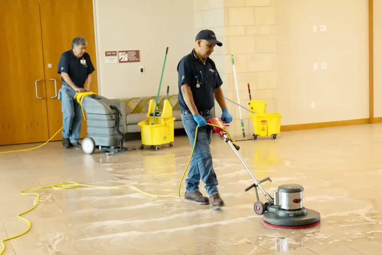 Workers using floor scrubbing machine to clean tile floors.