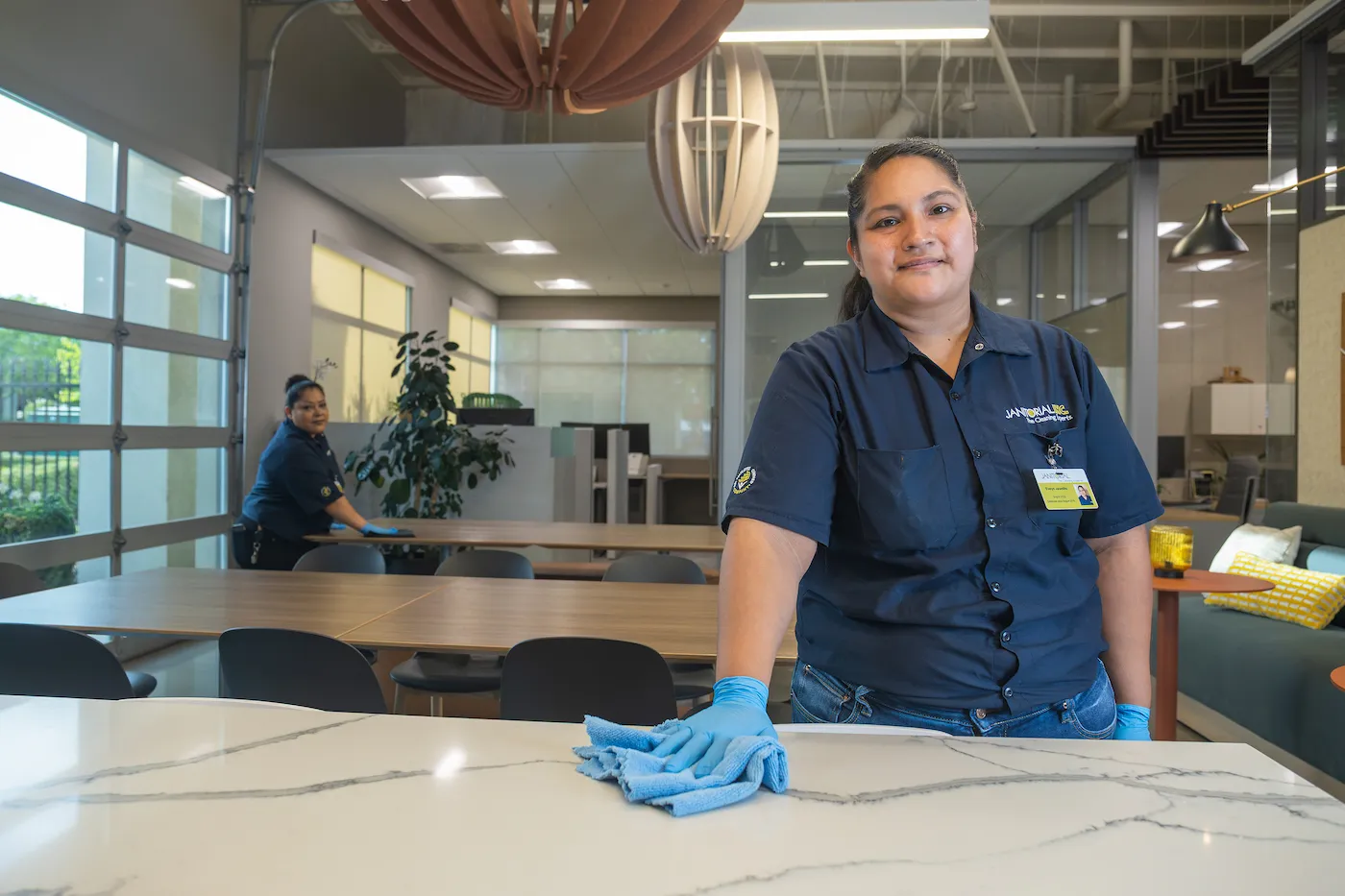 Two commercial cleaning employees wiping down an table in an office.