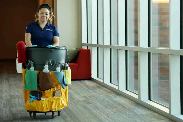 Commercial employee pushes cleaning bin through school hallway