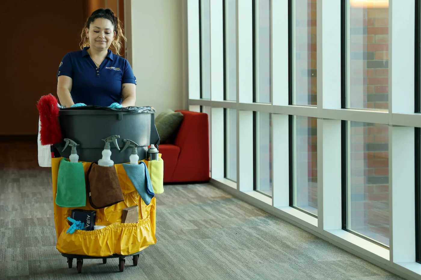 Commercial employee pushes cleaning bin through school hallway