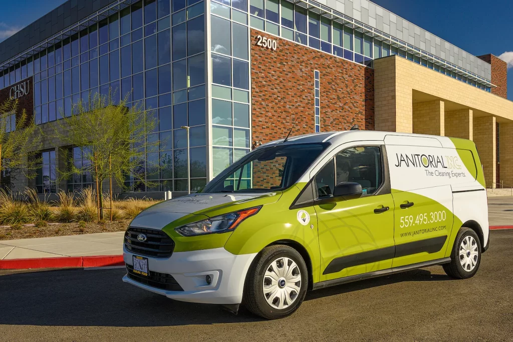 Janitorial Inc service van parked outside a medical school building.